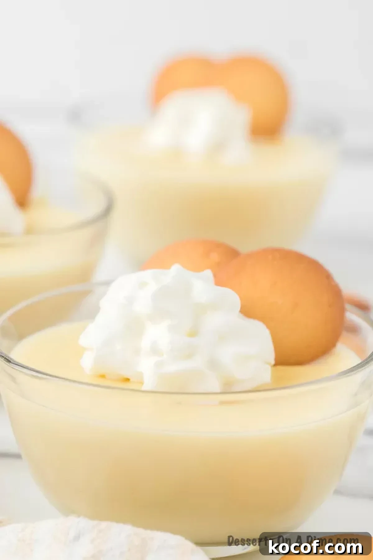 Vanilla pudding topped with whipped cream and vanilla wafers in a glass bowl
