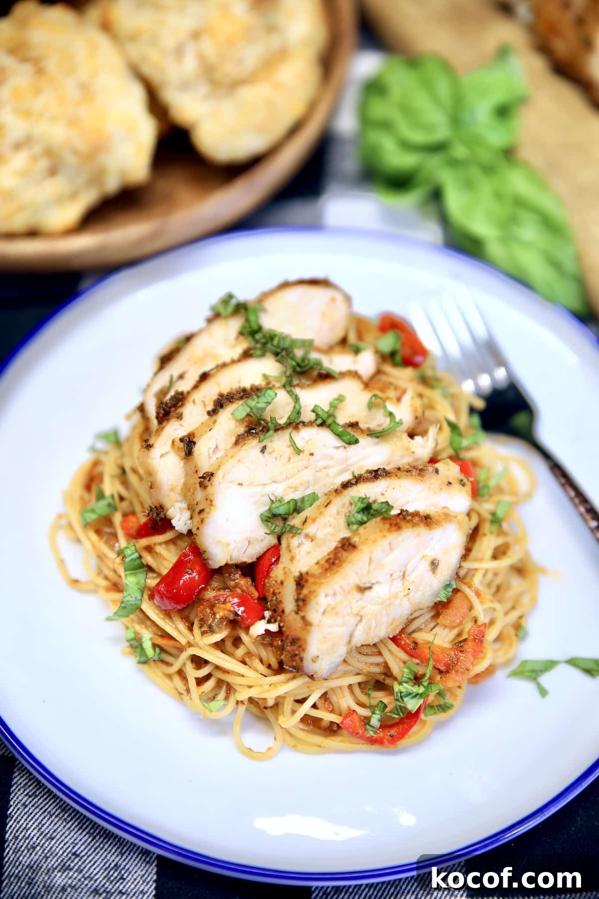 Grilled Chicken Spaghetti with homemade red sauce is filled with vegetables for a hearty meal that is sure to be a real family pleasing dinner. The grilled chicken adds amazing flavor to the spaghetti and can be cooked ahead for busy weeknights. Plate of spaghetti topped with sliced chicken.