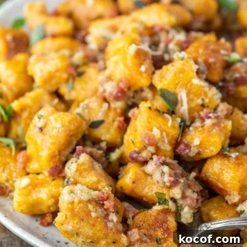 Fork dipped in pumpkin gnocchi on speckled plate.