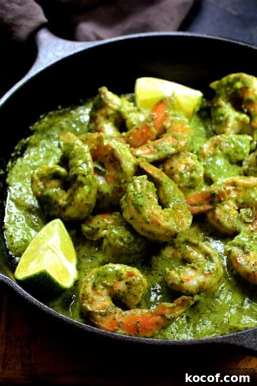 Garlic Butter Shrimp Served in Creamy Avocado Halves 6 Photo of Shrimp in Avocado Butter in cast iron skillet garnished with lime wedges.