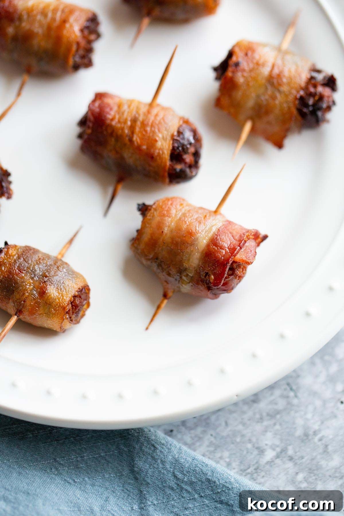 Crispy Air Fryer Stuffed Dates with Goat Cheese & Bacon 7 Cooked bacon wrapped dates on a plate.