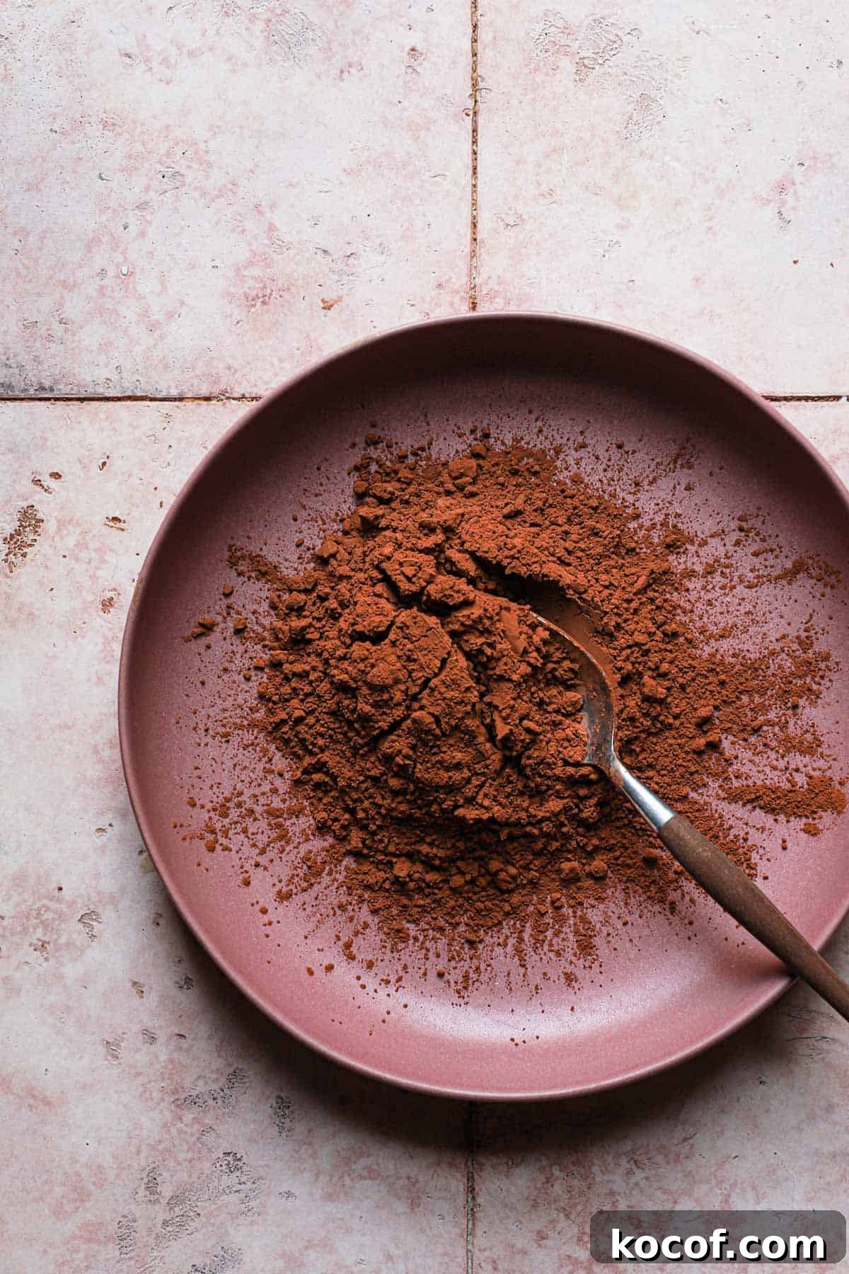 A bowl full of natural cocoa powder and a spoon.