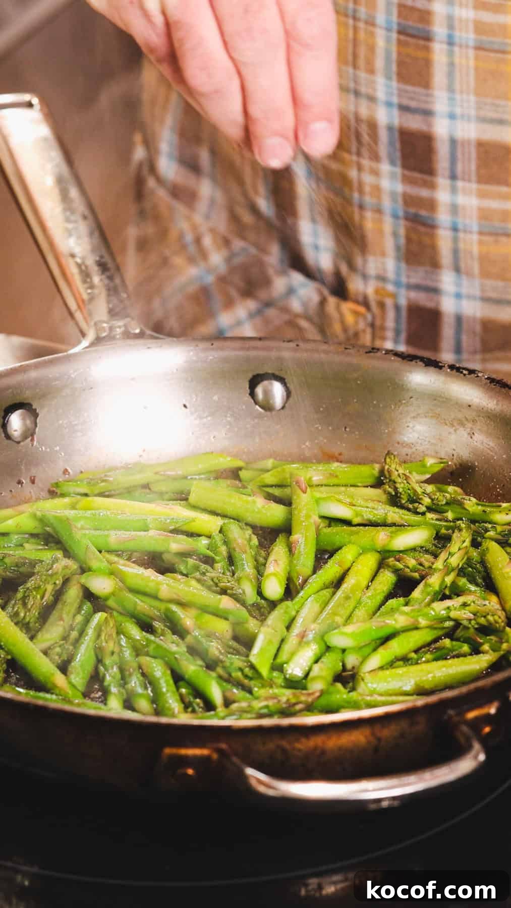 Creamy Bacon and Asparagus Pasta Recipe for Spring Meals 5 Asparagus cut into 2-inch pieces cooking in a large skillet and a hand seasoning it with salt.