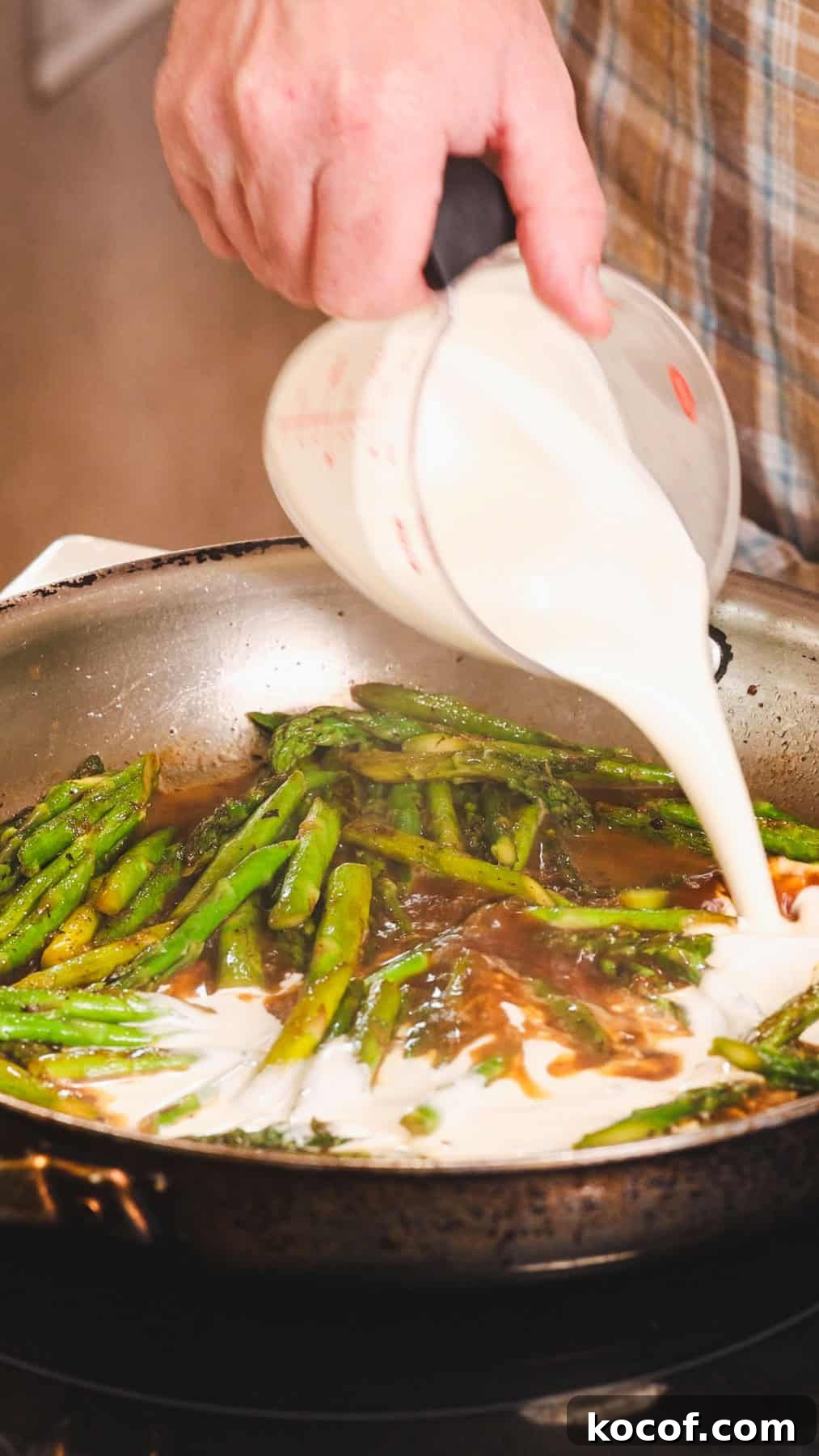 Creamy Bacon and Asparagus Pasta Recipe for Spring Meals 6 Heavy cream getting poured into a skillet with asparagus for a bacon and asparagus pasta.