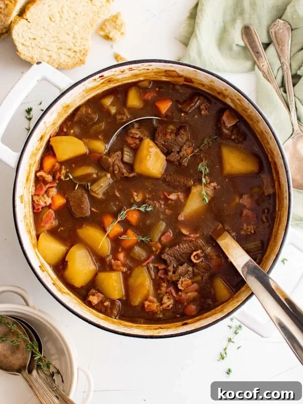 Large soup pot filled with Guinness beef stew filled with chunks of beef, potatoes, carrots, and garnished with fresh thyme.