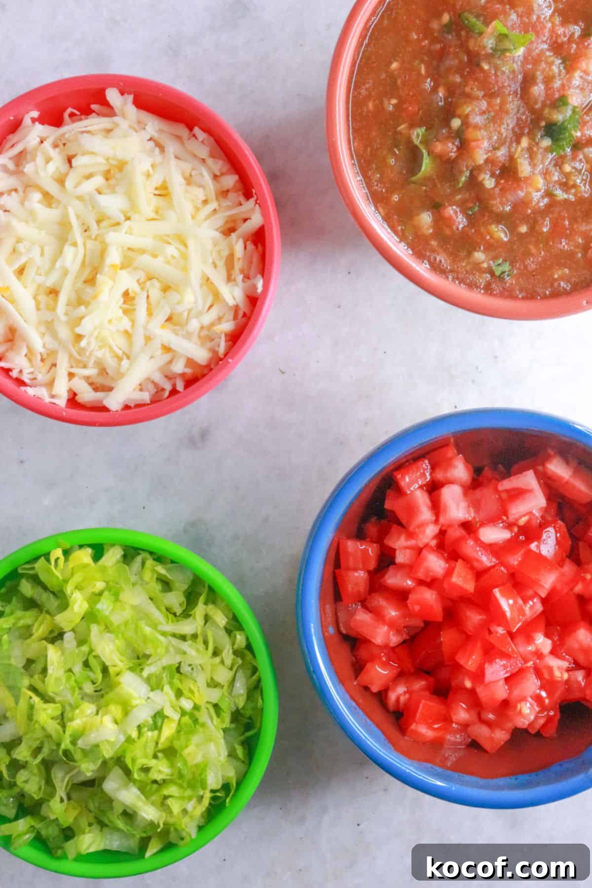 Refried Bean Tostadas with Crispy Tortillas and Fresh Salsa 6 A bowl with shredded cheese, a bowl with jalapeño salsa, a bowl with shredded lettuce, a bowl with diced tomato