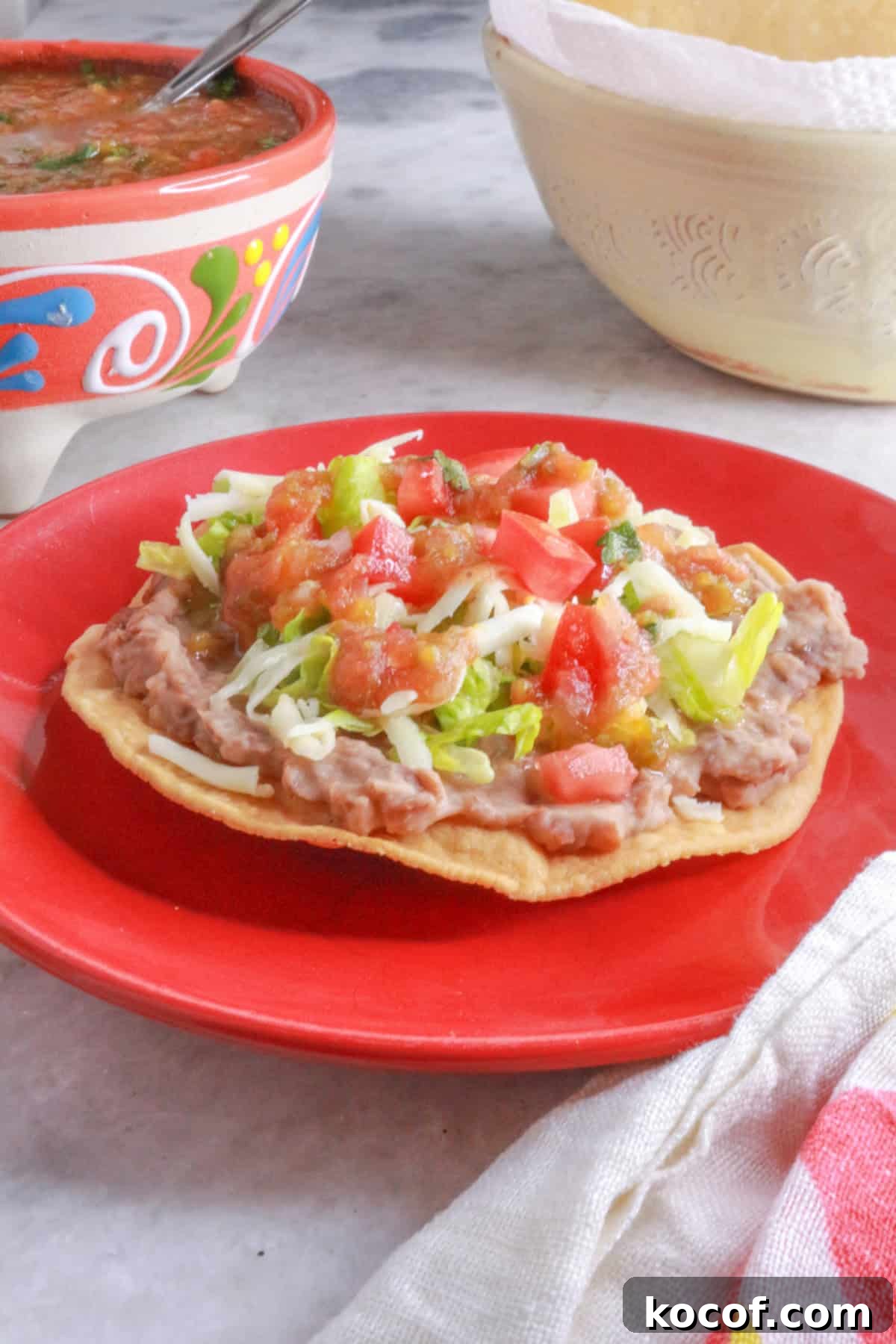 Refried Bean Tostadas with Crispy Tortillas and Fresh Salsa 10 A red plate with a tostada de frijoles (bean tostada)