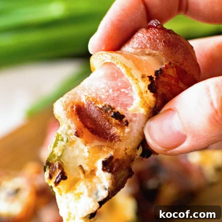 Bacon-Wrapped Jalapeño Poppers: Baked or Grilled Recipes 6 Hand holding grilled bacon wrapped jalapeno popper