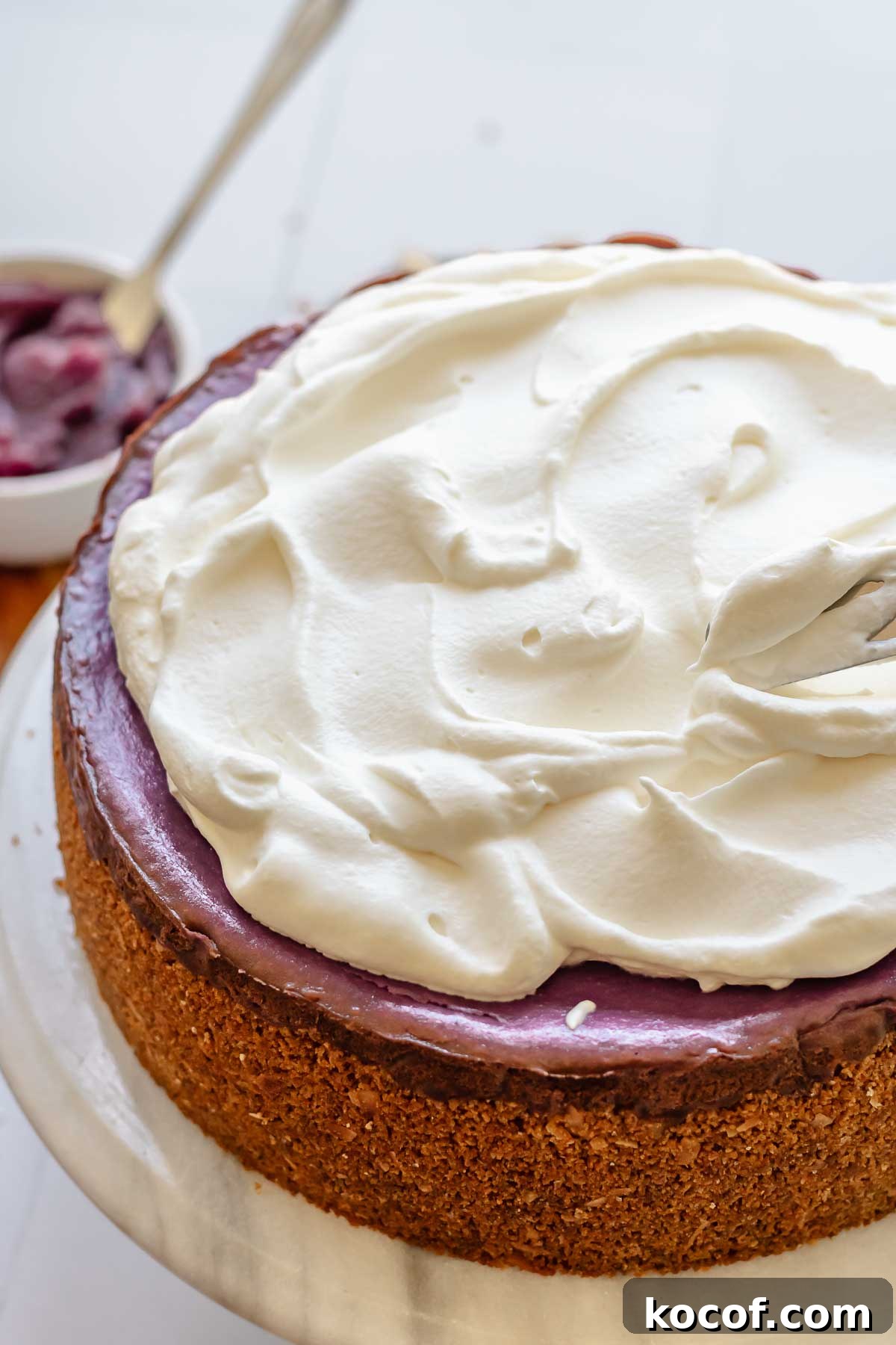 Creamy Ube Cheesecake Recipe: Filipino Purple Yam Dessert 13 Coconut whipped cream spread on top of use cheesecake.