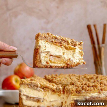 A hand holds a piece of apple cheesecake on a pie server.