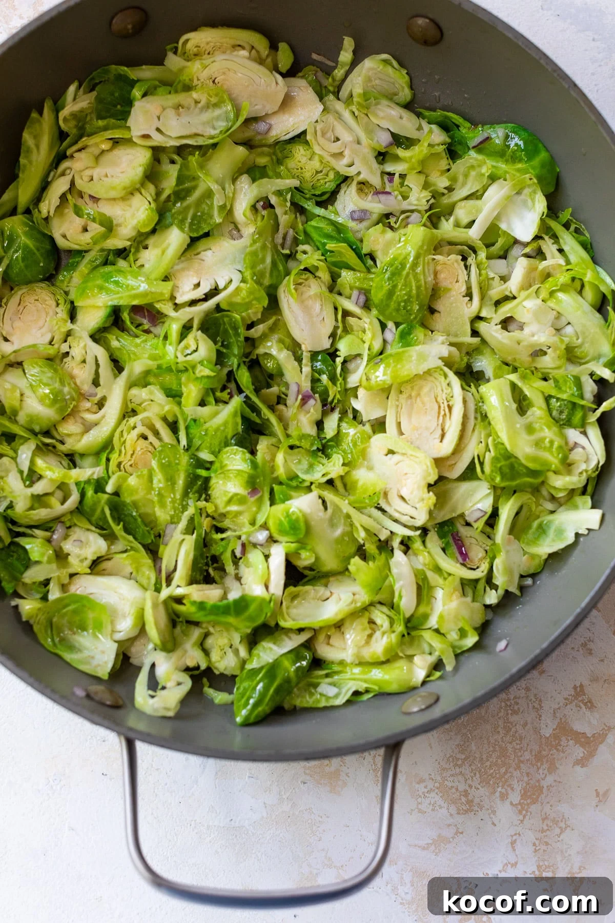 shaved brussels sprouts cooking in a skillet.