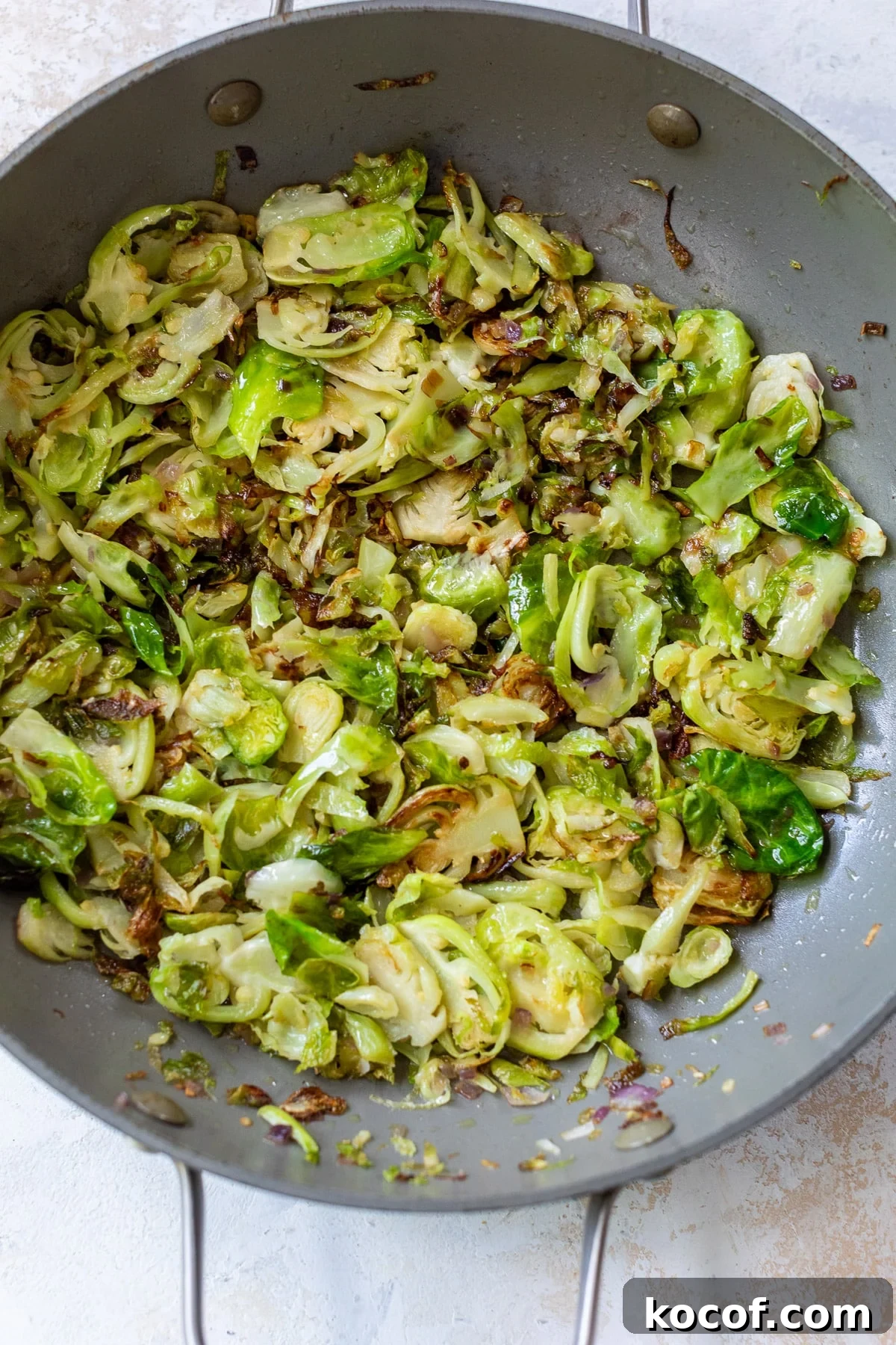 shaved brussels sprouts cooking with garlic in a skillet.