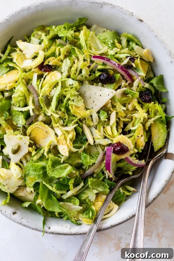 brussels sprouts slaw in a bowl with a fork and spoon