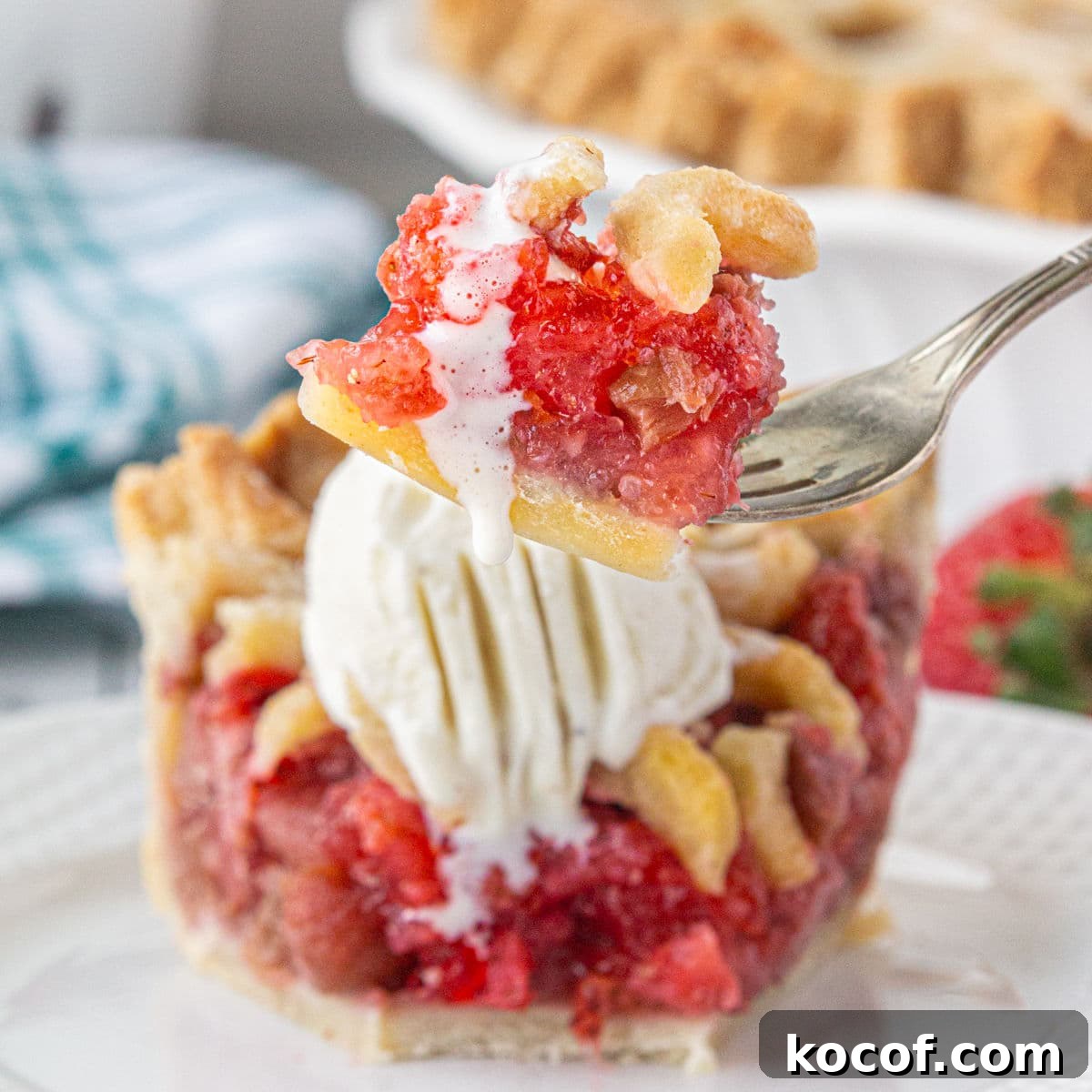 Classic Summer Strawberry Dessert Recipes You’ll Love 8 A slice of strawberry rhubarb pie with vanilla ice cream melting on top.