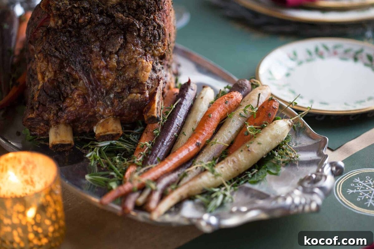 Herb-Roasted Prime Rib Roast: Tender, Juicy Holiday Recipe 5 roasted carrots on a metal platter next to a prime rib.