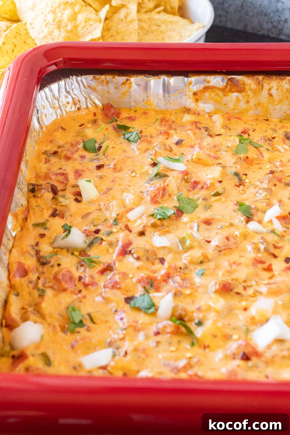 Smoked Queso in an aluminum pan with chips in the background.