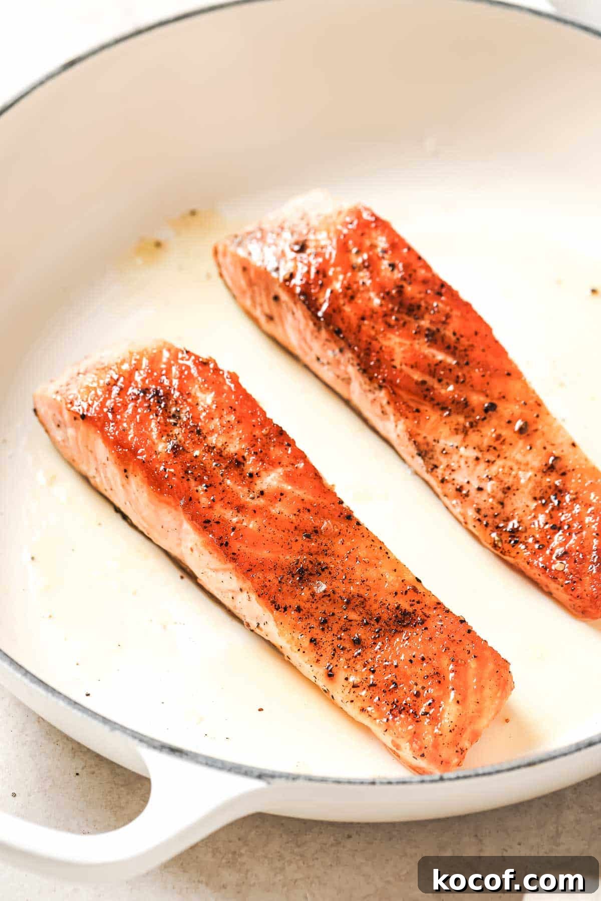 Two salmon fillets in a frying pan.