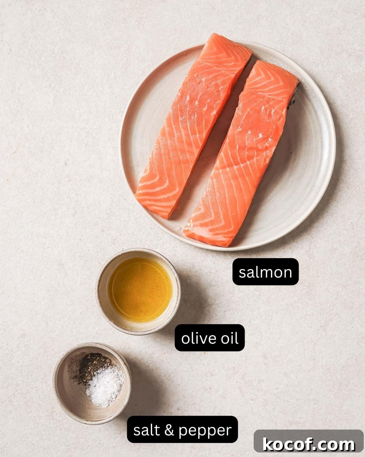 Salmon fillets with olive oil, salt, and pepper on a countertop.
