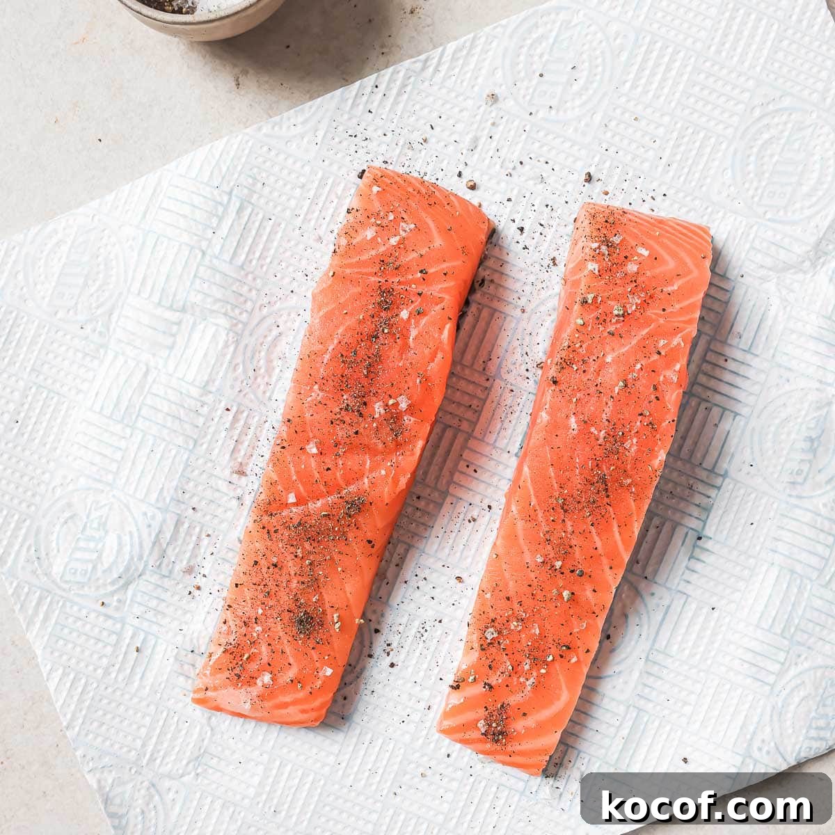 Two pieces of salmon on a paper towel.