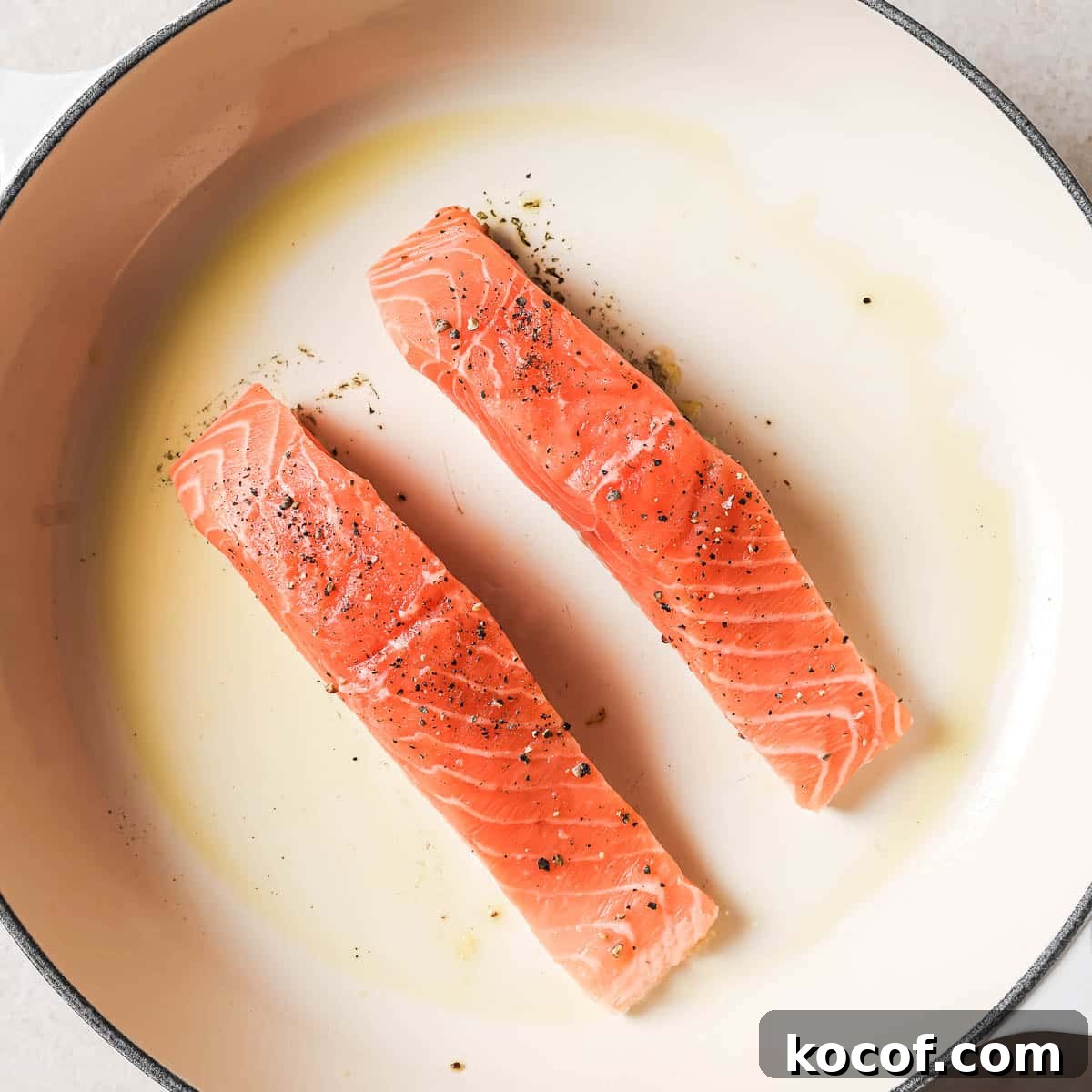 Two salmon fillets in a frying pan.