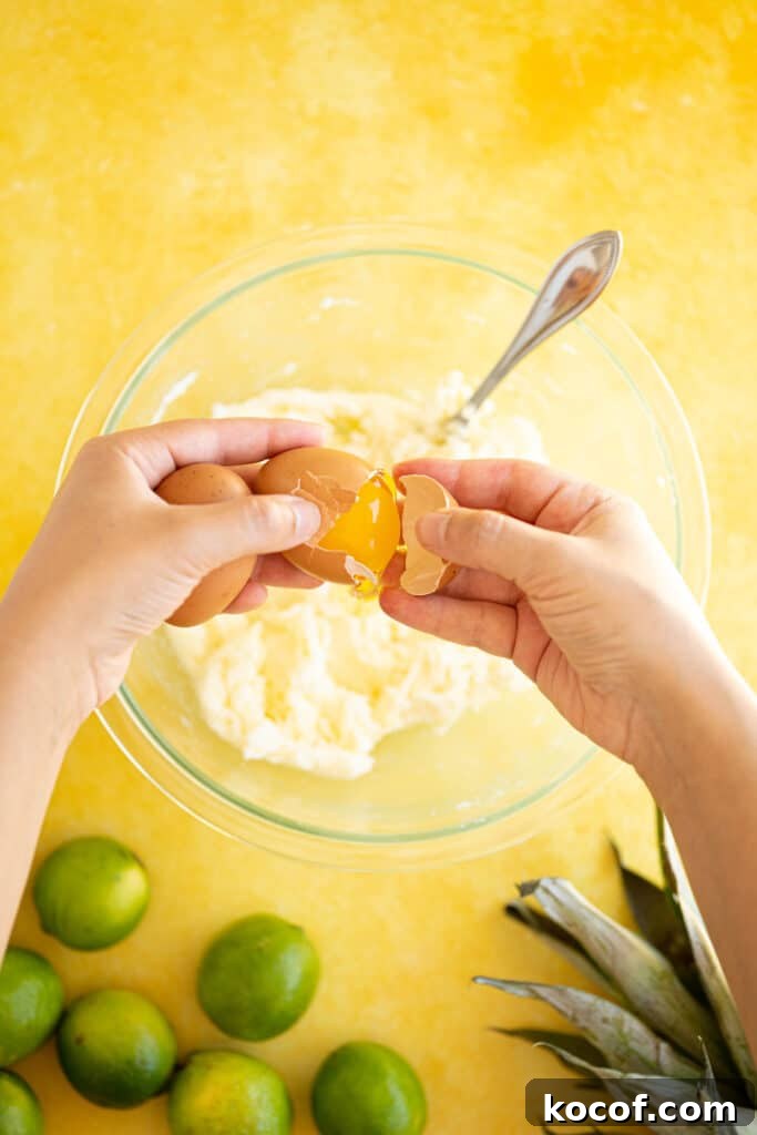 Moist Piña Colada Cake with Fresh Pineapple and Coconut 4 eggs cracking into a bowl