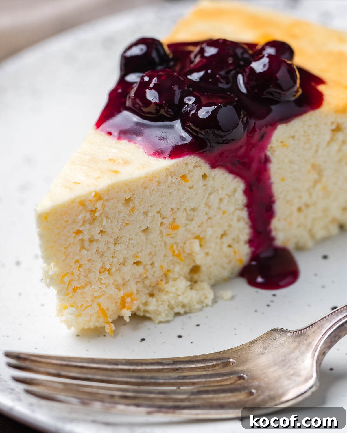 Authentic Italian Cheesecake Recipe: Classic Torta della Nonna Style 2 Closeup shot of Italian cheesecake with blueberry sauce on white plate.