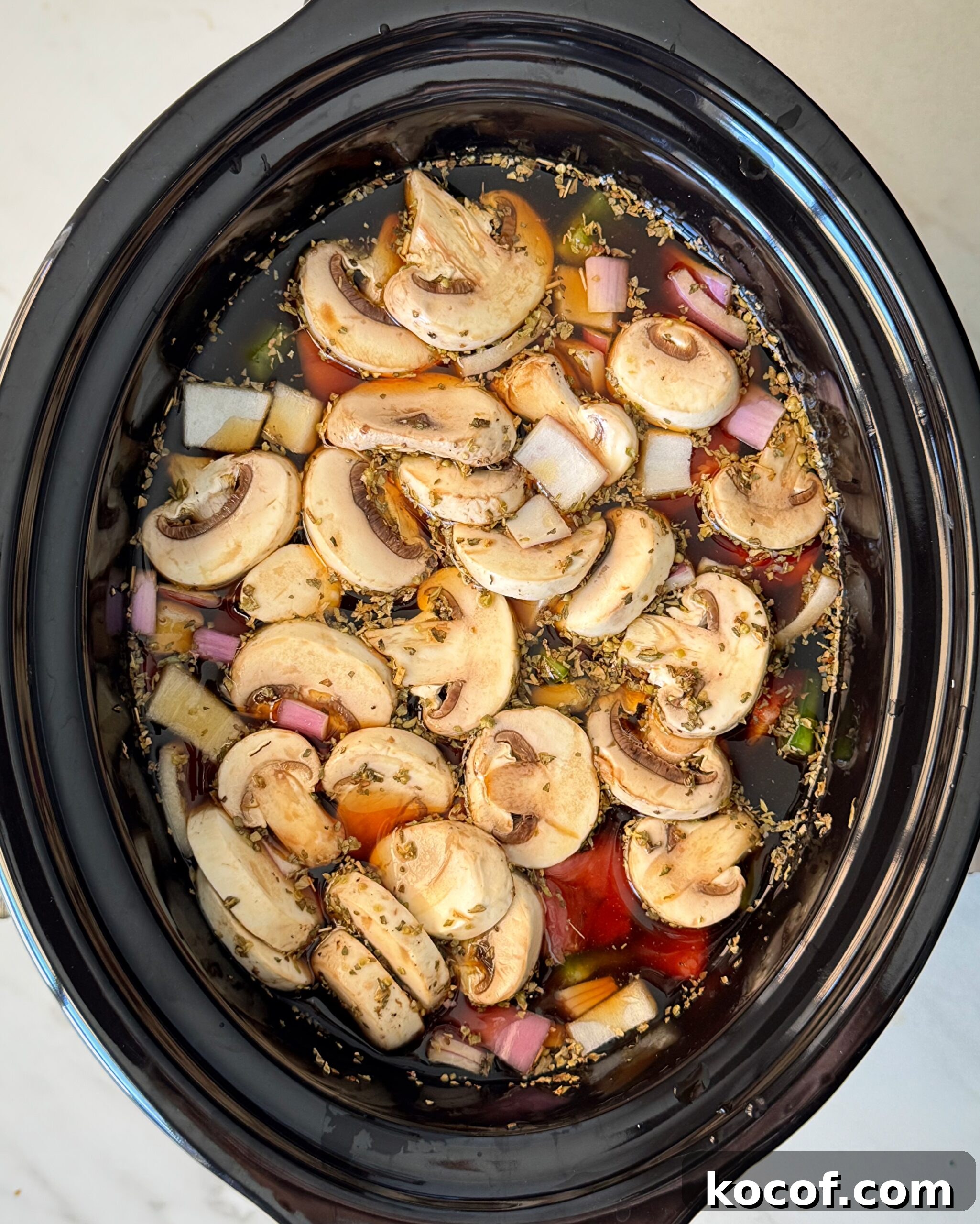 overhead shot of uncooked beef kebab soup in a black slow cooker