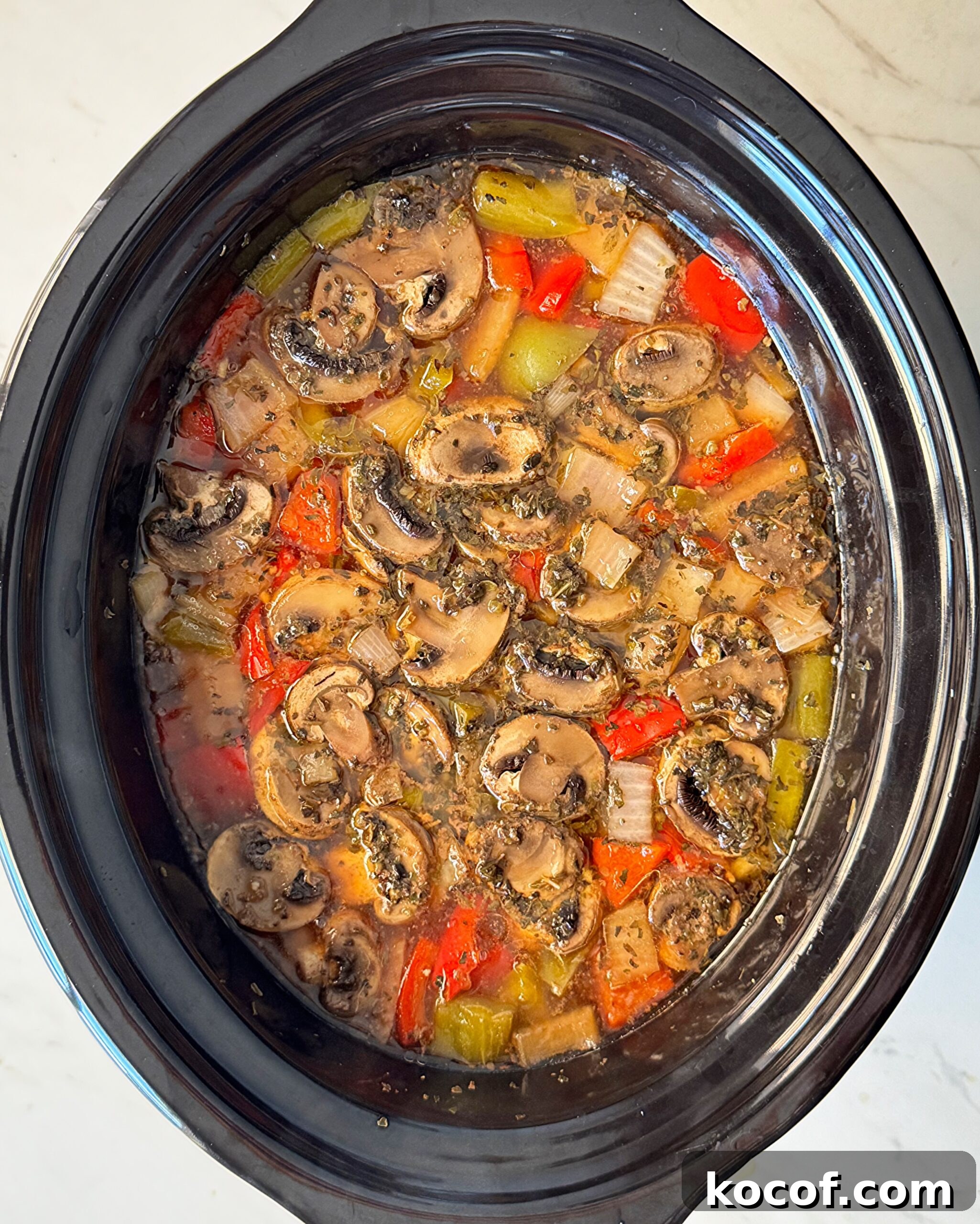 overhead shot of cooked beef kebab soup in a black slow cooker