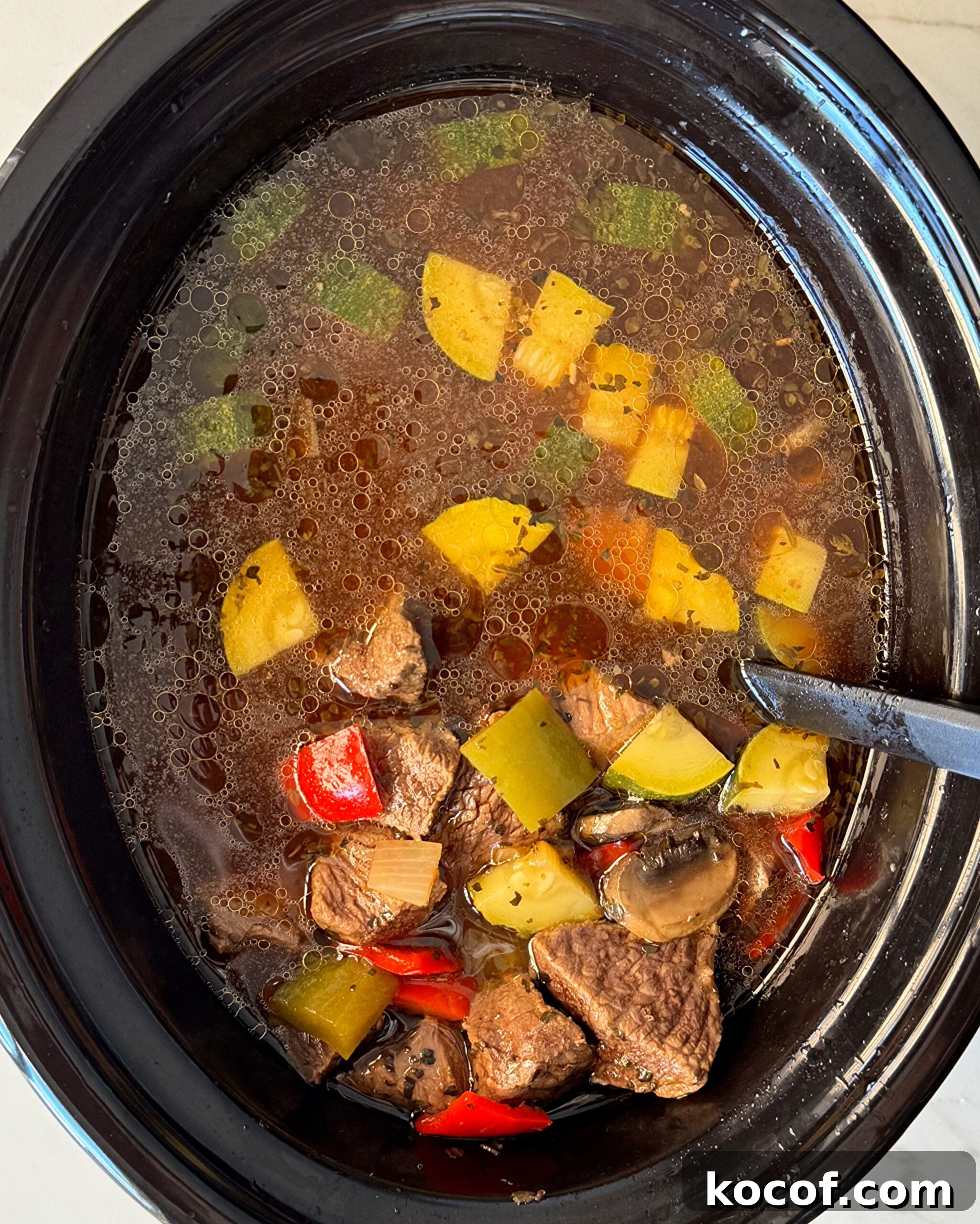overhead shot of cooked beef kebab soup in a black slow cooker