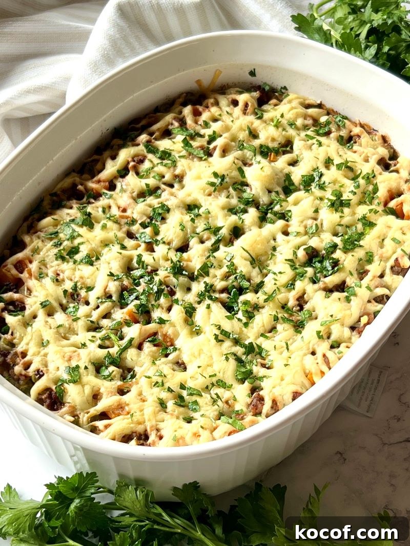 Ground beef rice casserole baked in an oval casserole dish with melted cheese on top.