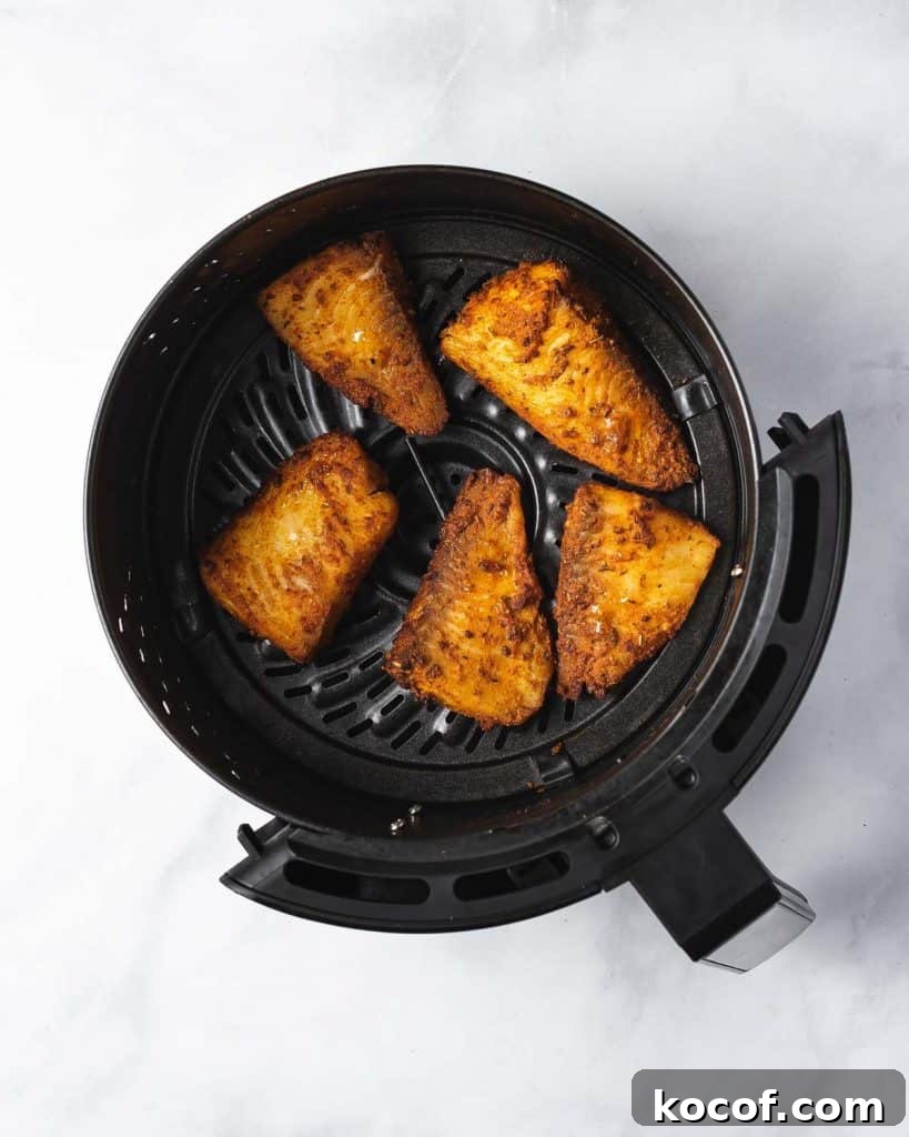 Air fryer basket with air fried fish.