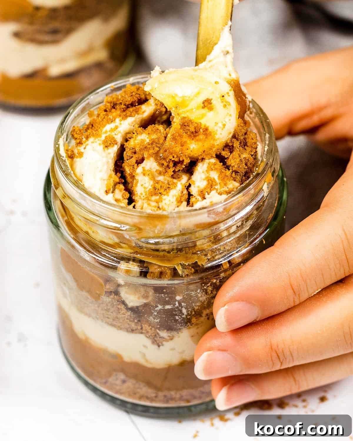 Someone taking a mouthful of a biscoff banoffee pie cup.