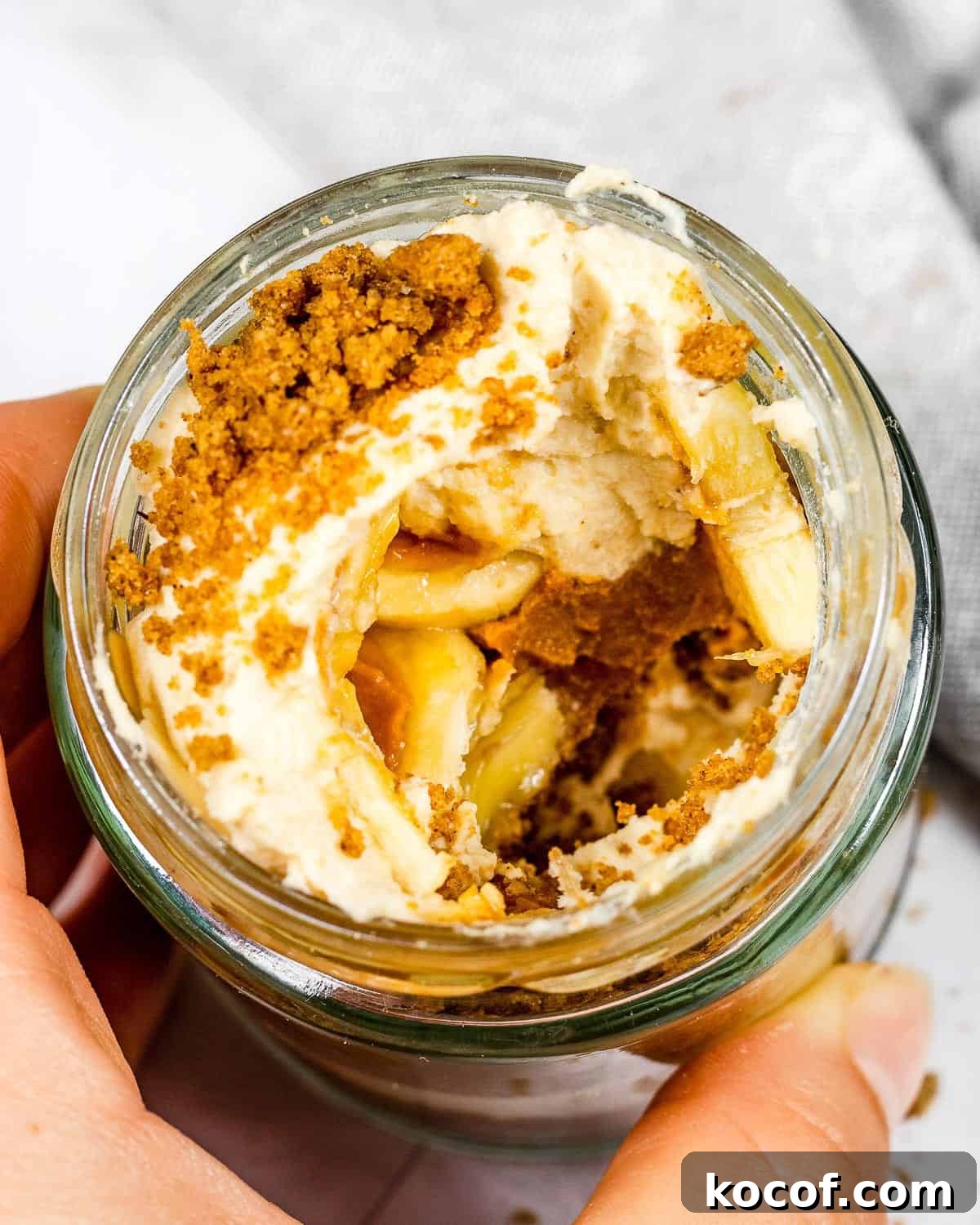 A half-eaten biscoff banoffee pie cup, revealing the inside.