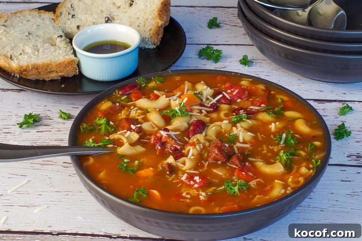 leftover ham macaroni soup in a black bowl, with more black bowls in the background and onion and olive bread with bread and oil