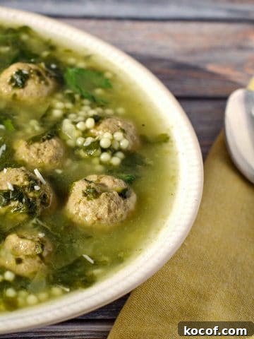 Easy Italian wedding soup with frozen meatballs on a bluish wooden background with a yellow napkin and spoon