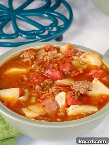 Hamburger soup in a green bowl with pot holder in background