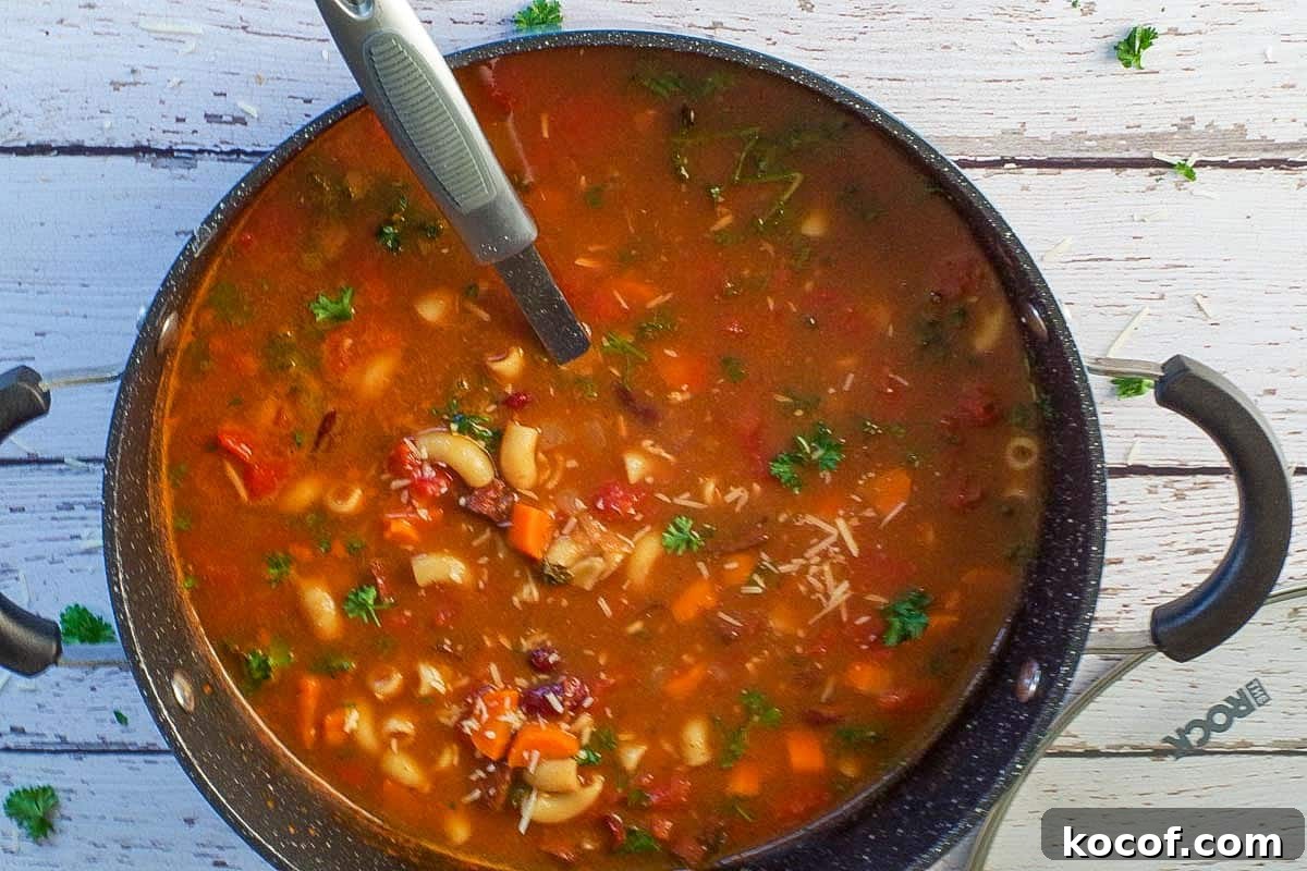 Cooked Ham and Macaroni soup with parmesan cheese and garnish in a large pot with a ladle
