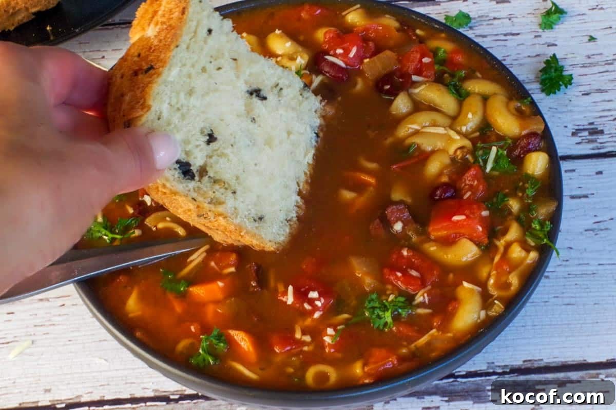 onion and olive bread being dipped into leftover ham macaroni soup in a black bowl