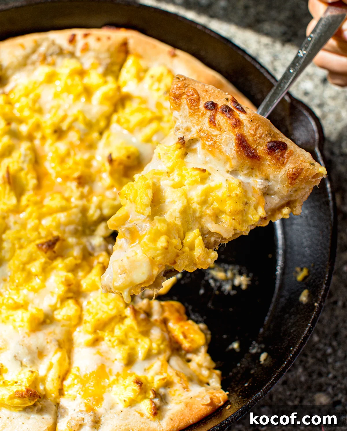 a slice of homemade breakfast pizza made from a homemade pizza dough recipe and sausage gravy, cheese, and scrambled eggs #eggs #sausage #breakfast #pizza #recipe #egg #crust how to make the best breakfast pizza recipe