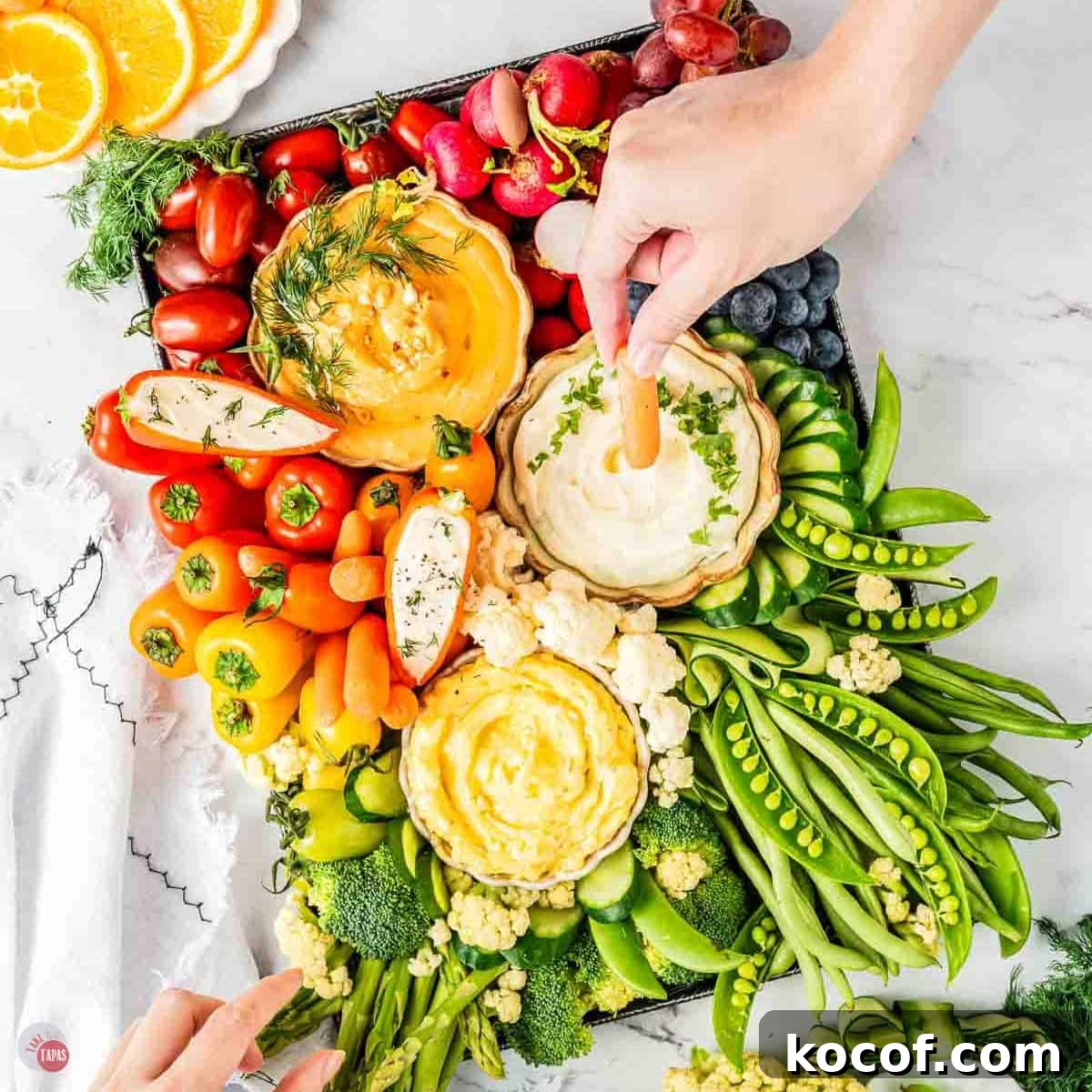 Colorful vegetable platter featuring cherry tomatoes, bell peppers, cucumbers, and dips.