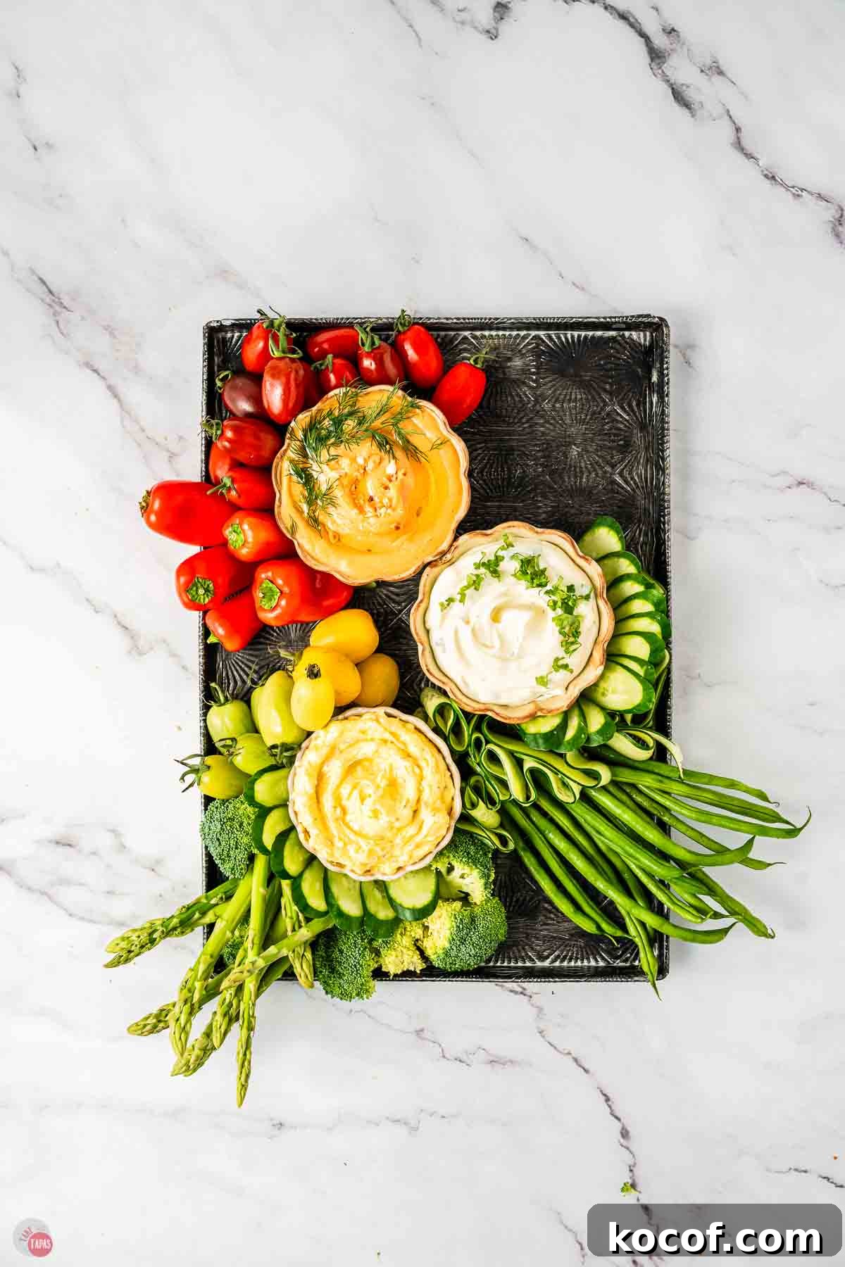 Fresh vegetable platter with three bowls of dips