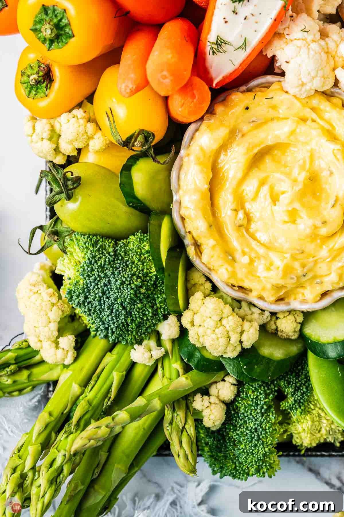 close up of green vegetables and a bowl of hummus