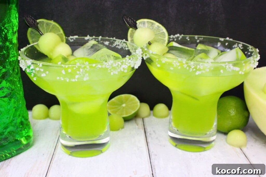 two midori margaritas with fresh fruit against a dark background