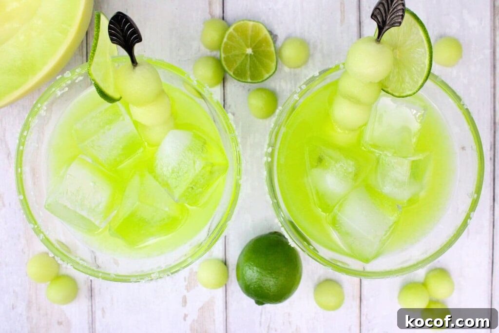 overhead view of two midori margaritas with fresh lime and melon balls
