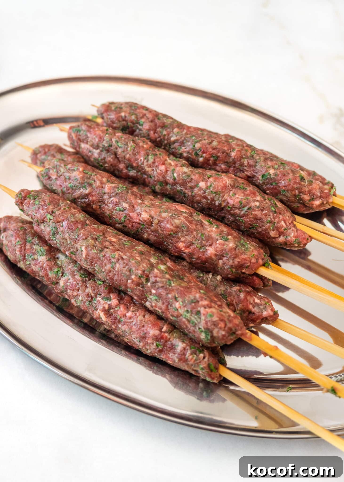 Authentic Kafta Kebab Recipe: Juicy Middle Eastern Grilled Skewers 4 Raw Kafta kebabs on platter.