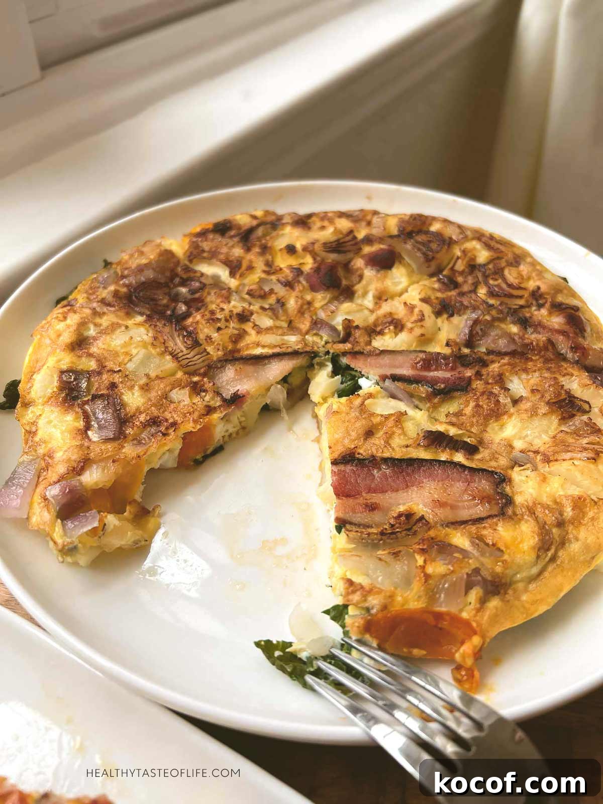 Veggie omelette with cauliflower and bacon sliced and a wedge taken out.