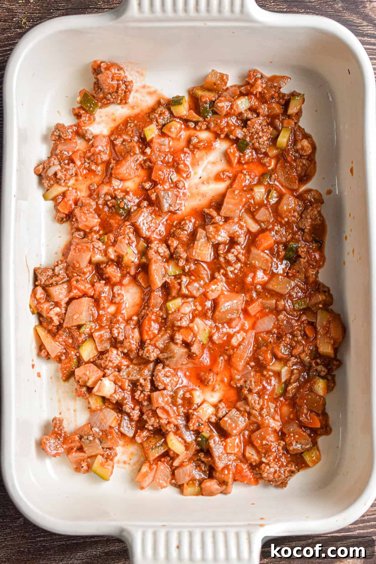 The tomato sauce is added to the bottom of a 9x13 inch pan.