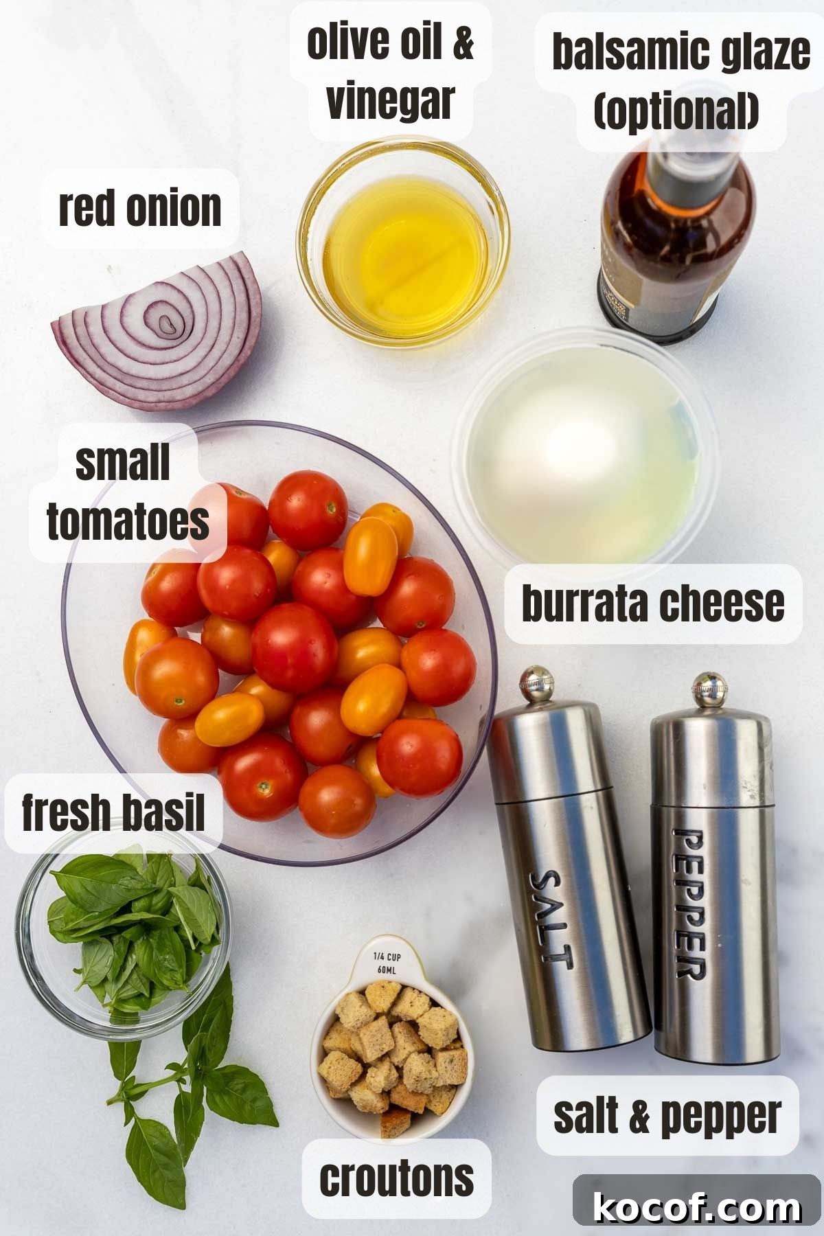 Overhead view of all the ingredients including cherry tomatoes, fresh basil, red onion, a mixture of olive oil and vinegar, optional balsamic glaze and salt and pepper, all on a marble background.