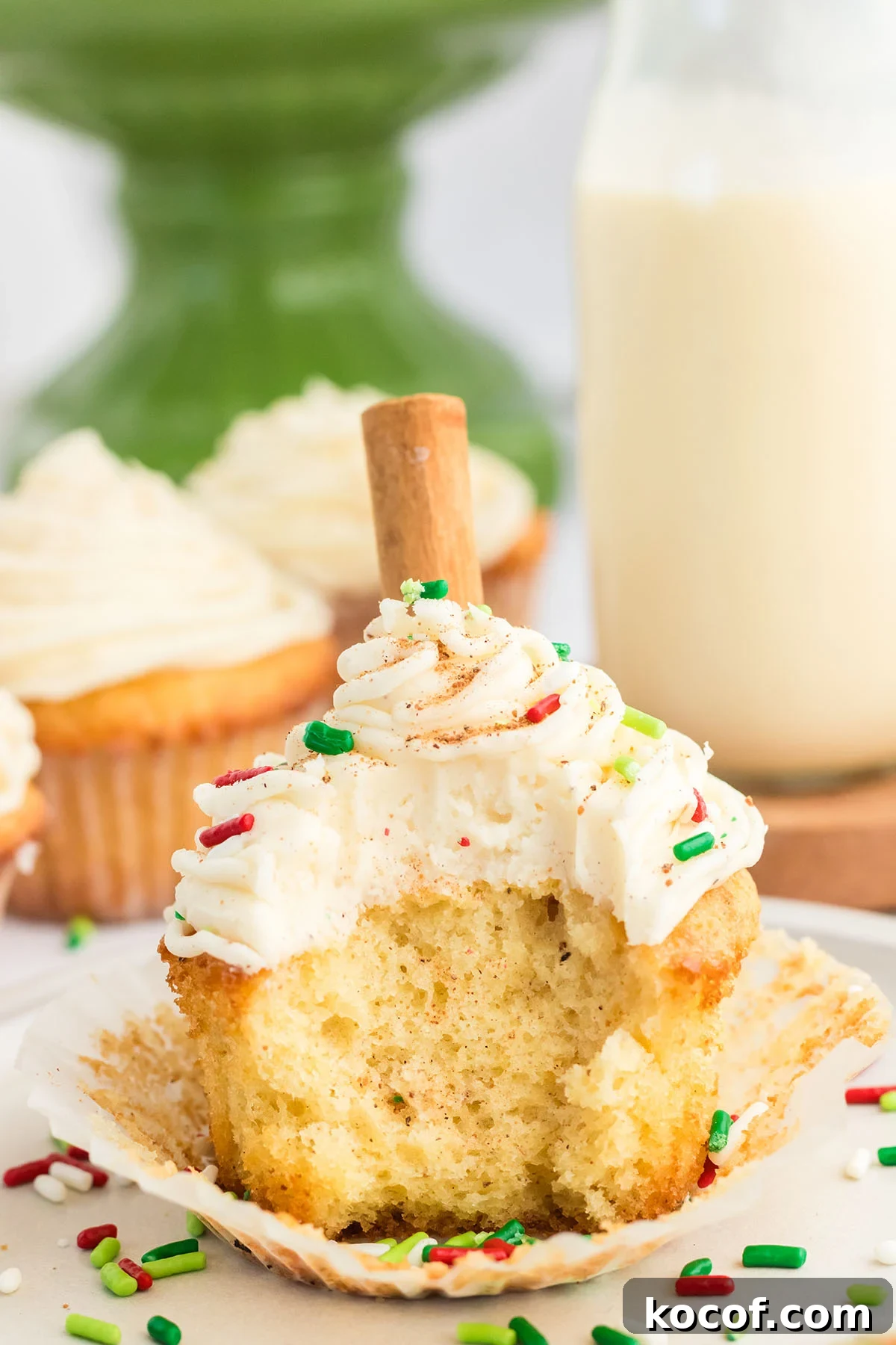 Eggnog cupcake topped with sprinkles with a bite taken out of it.