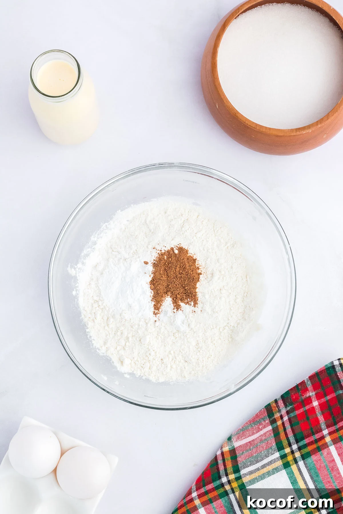 Flour, baking powder, salt, and nutmeg in a glass mixing bowl.
